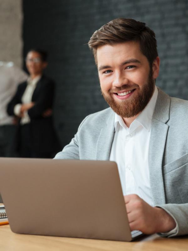 cheerful-young-caucasian-accountant sitting at desk with laptop